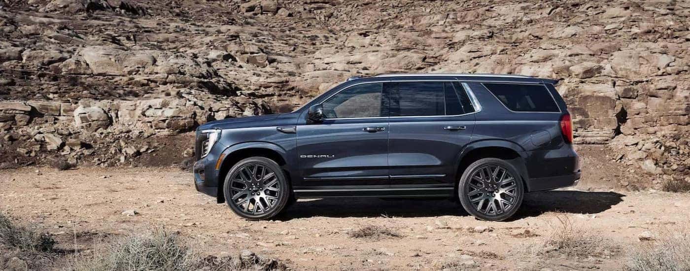 A blue 2025 GMC Yukon Denali is shown parked off-road.