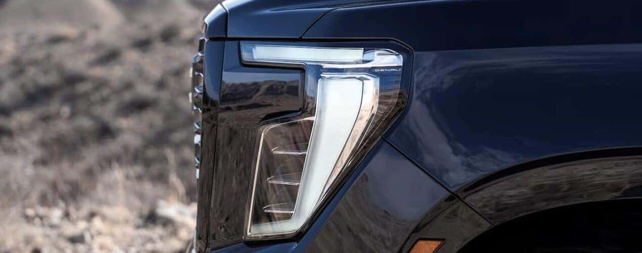 A close-up of a headlight is shown on a black 2025 GMC Yukon Denali.