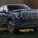 A blue 2025 GMC Sierra 1500 Denali parked on grass.