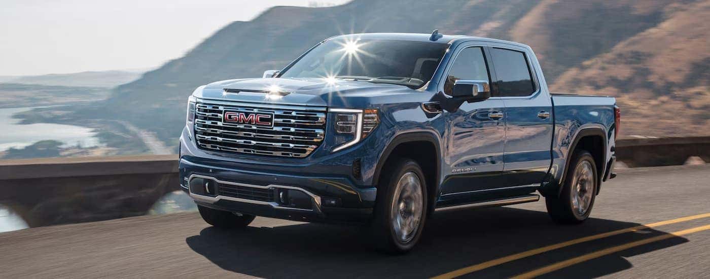 A blue 2025 GMC Sierra 1500 Denali driving down a highway