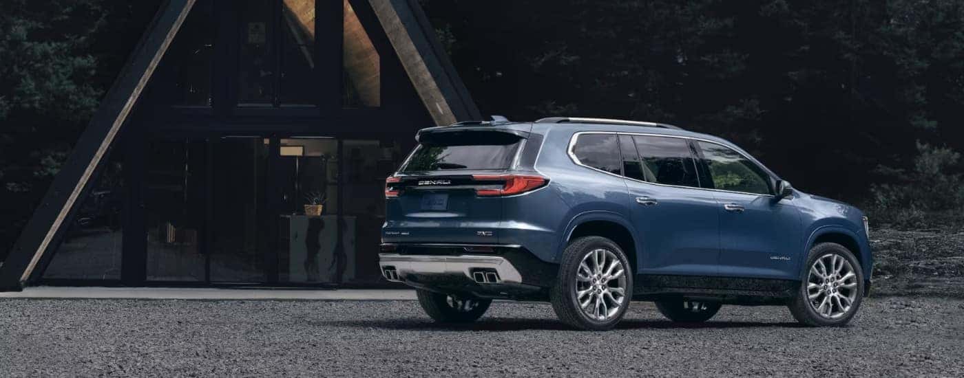 A blue 2024 GMC Acadia Denali is shown parked near a house after visiting a GMC dealer near Duluth.