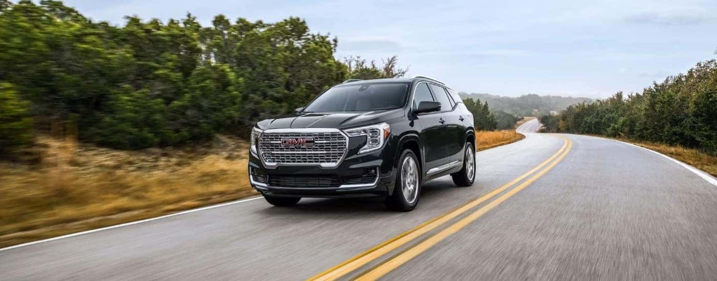 A black 2022 GMC Terrain Denali angled left and driving down a road.