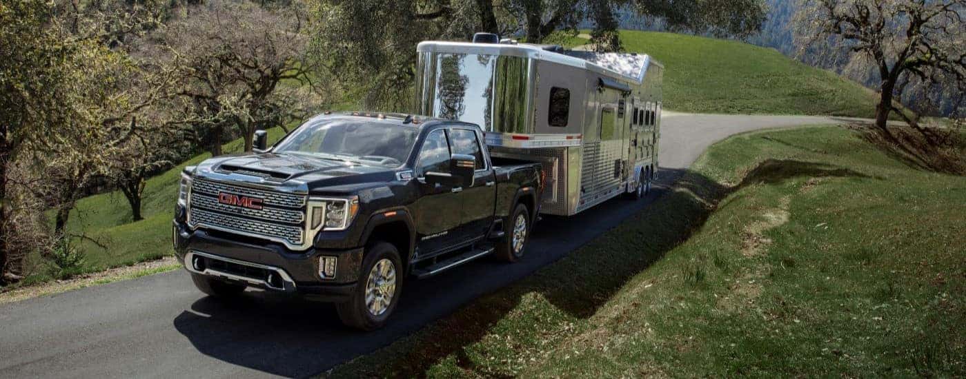 A black 2021 GMC Sierra 2500HD Denali is shown towing a trailer after looking at GMC trucks for sale.