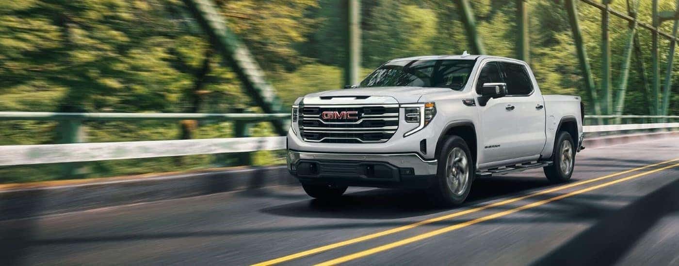 White 2024 GMC Sierra 1500 SLE driving across a bridge.