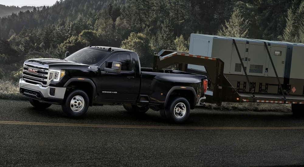 A black 2023 GMC Sierra 3500 HD work truck towing a trailer