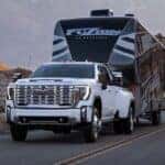 A white 2025 GMC Sierra 2500 towing a trailer.