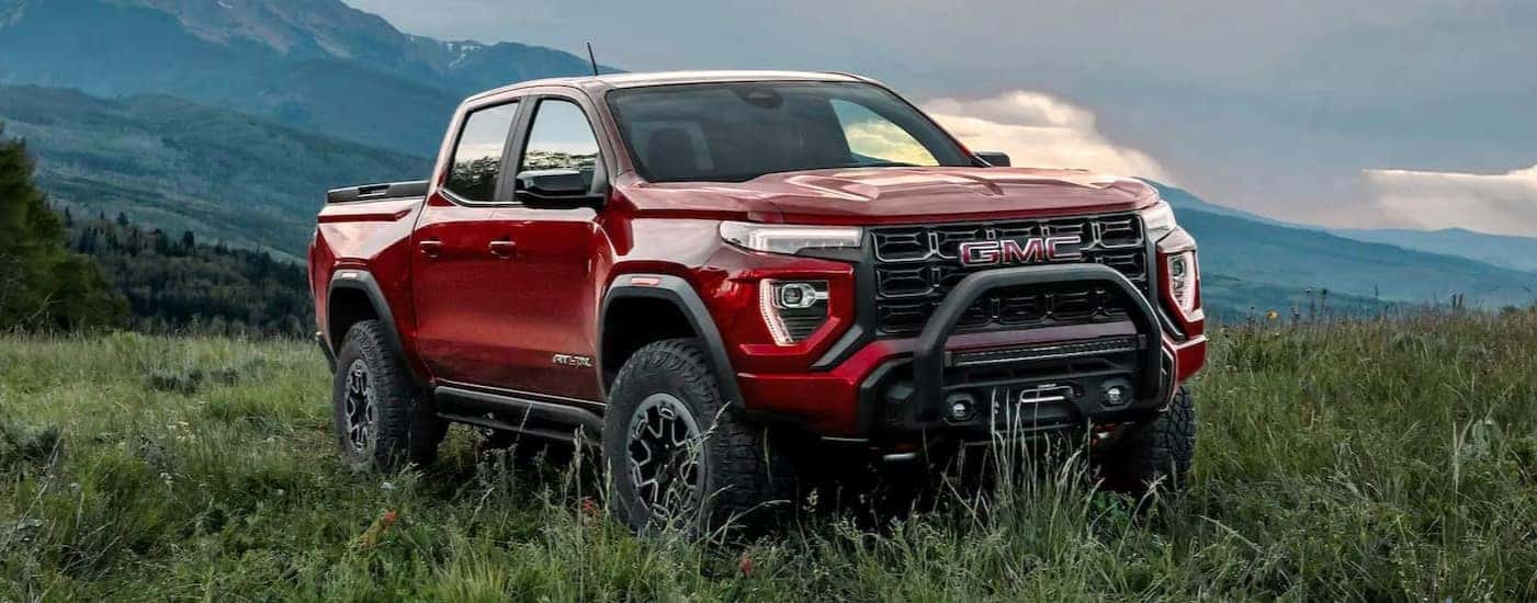 A red 2025 GMC Canyon AT4X parked on grass.