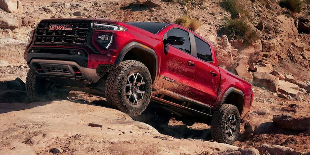 Red 2025 GMC Canyon driving up rocks.
