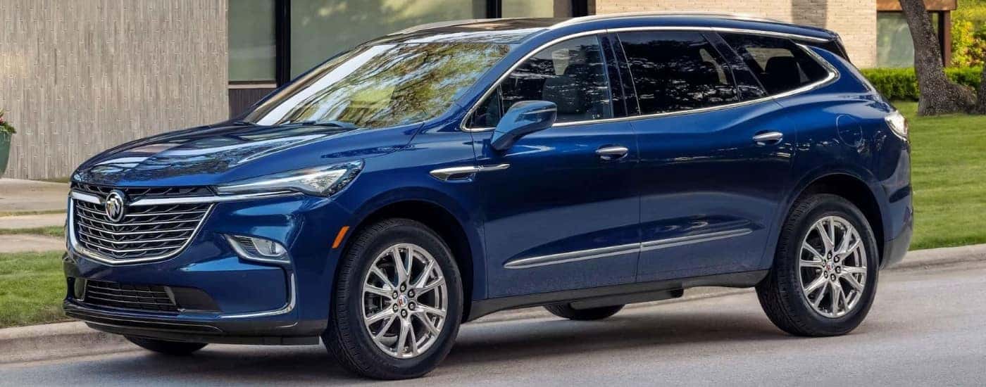 A blue 2024 Buick Enclave for sale is shown parked near a curb.