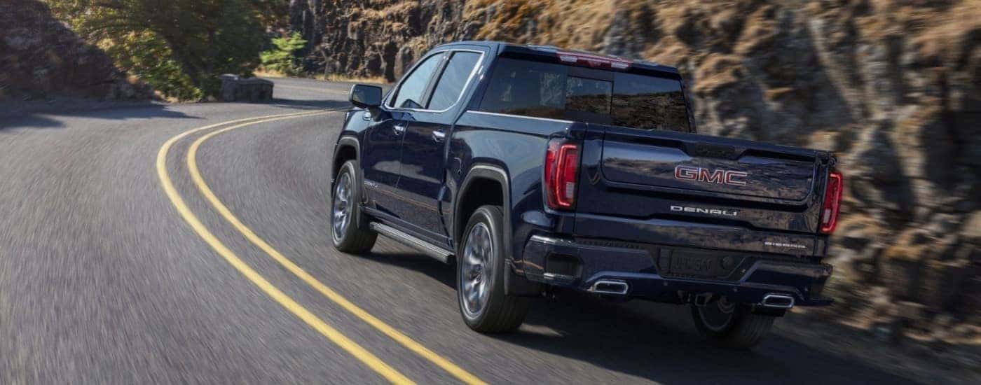 A blue 2024 GMC Sierra 1500 is shown from the rear at an angle after leaving a dealer that has a GMC Sierra for sale.
