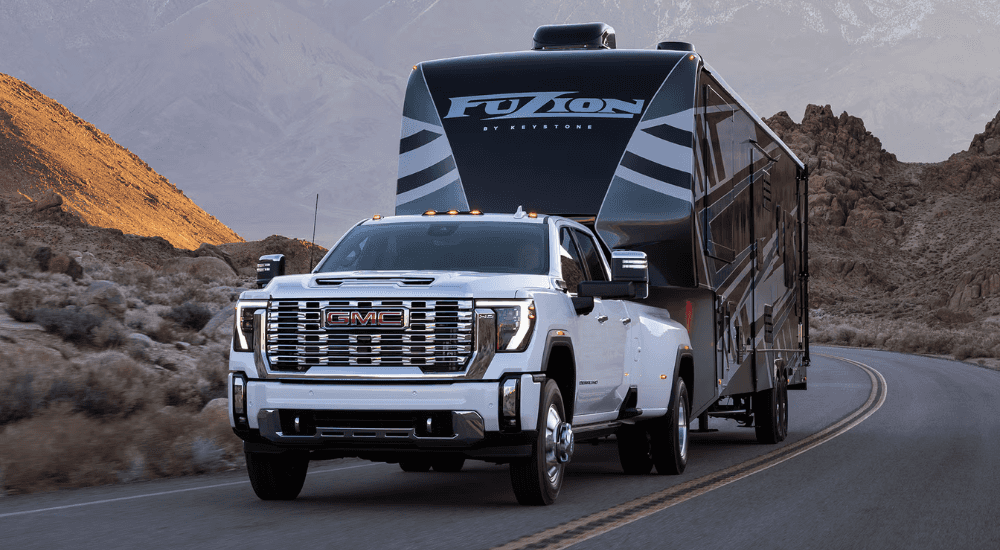 White 2026 GMC Sierra 1500 HD AT4 towing a camper