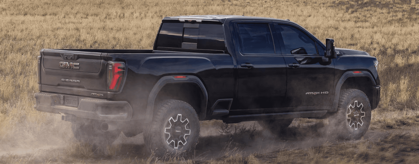 Black 2026 GMC Sierra 2500 HD driving down a trail