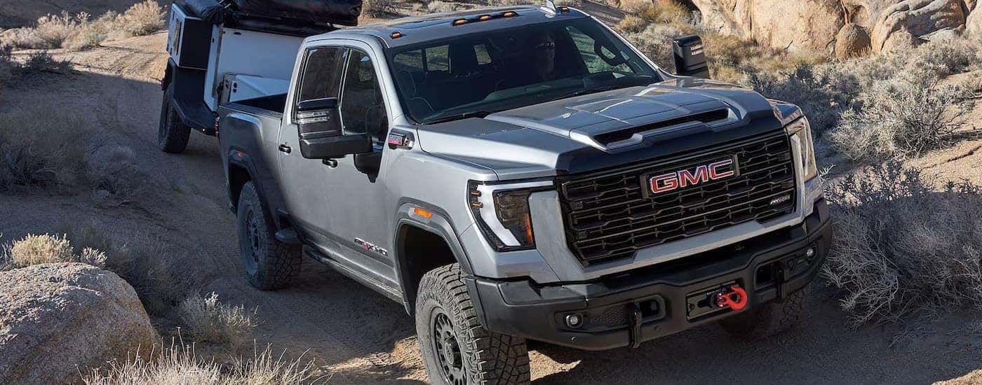 A silver 2026 GMC Sierra 2500 AT4X HD off-roading while towing a trailer