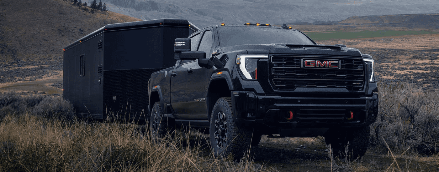Black 2026 GMC Sierra 2500 HD AT4X towing a trailer off-road
