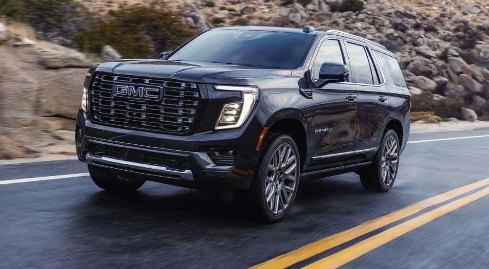 Black 2026 GMC Yukon Denali driving down a paved road