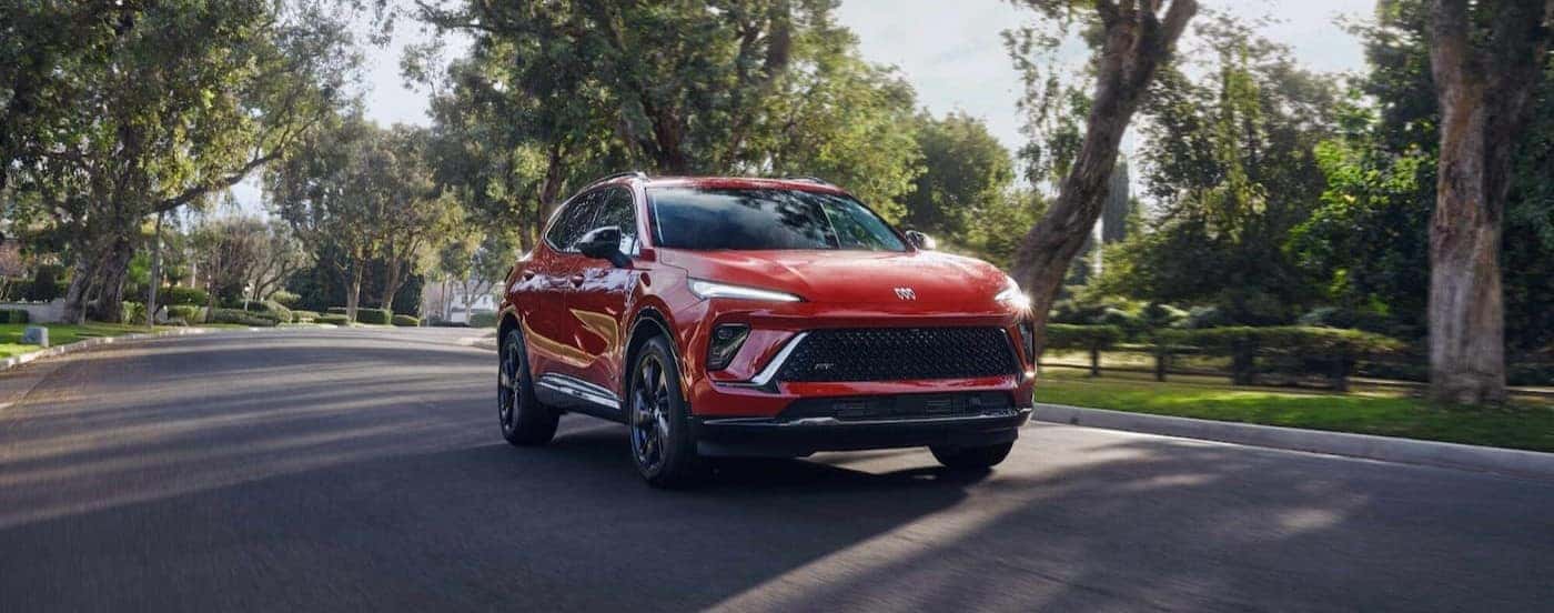 A red 2026 Buick Envision driving through a neighborhood.