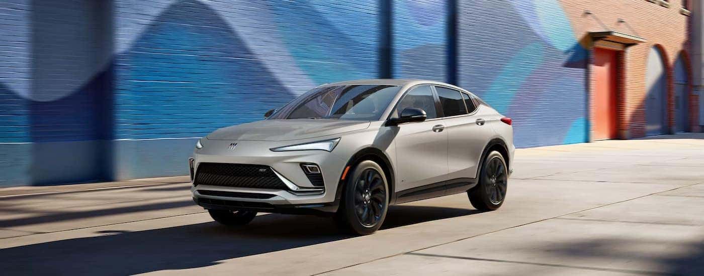 A silver 2026 Buick Envista driving by a colorful wall.