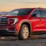 Red 2026 GMC Acadia parked on a dirt trail.