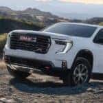 White 2026 GMC Acadia AT4 driving up rocks