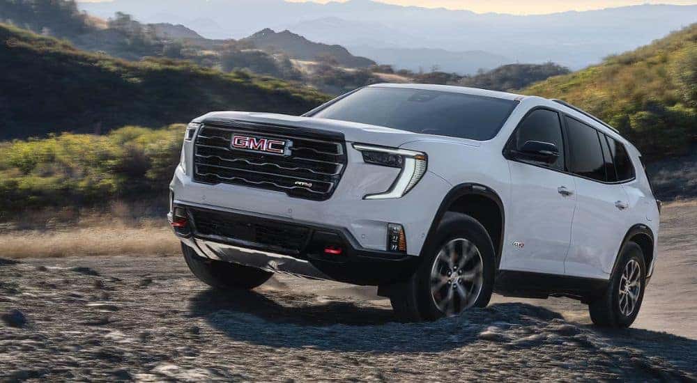 White 2026 GMC Acadia AT4 driving up rocks