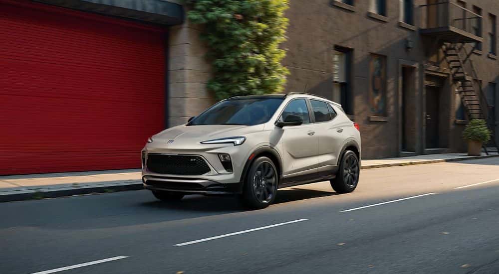 A ceramic-colored 2026 Buick Encore GX Sports Touring driving down a city street.