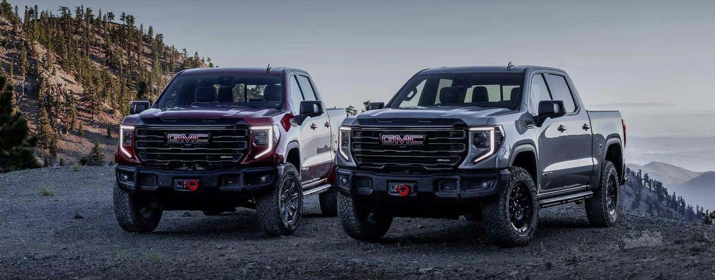 A re and a gray 2027 GMC Sierra 1500 AT4X parked off-road