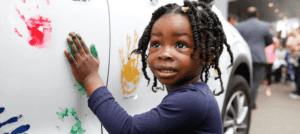 girl paints handprints on car for Hyundai Hope On Wheels