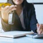 Woman with car keys using calculator