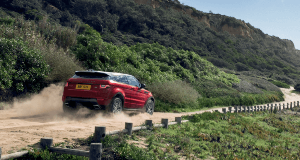 Red Range Rover on winding dirt mountain road.