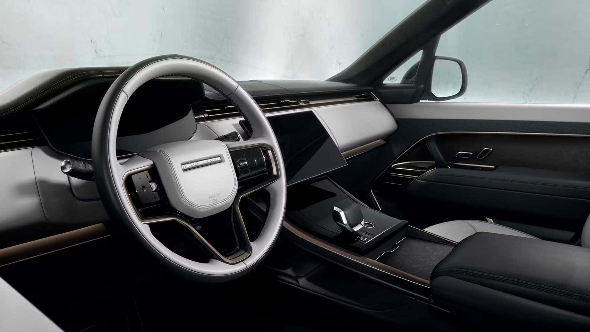 Modern Range Rover Sport interior featuring minimalist dashboard with digital displays and leather-wrapped steering wheel