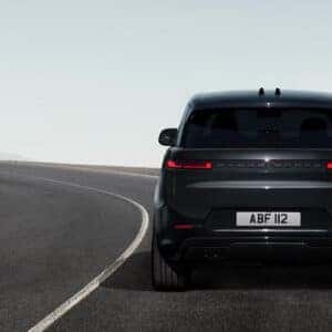 Rear view of dark Range Rover Sport on coastal mountain road showing distinctive taillights
