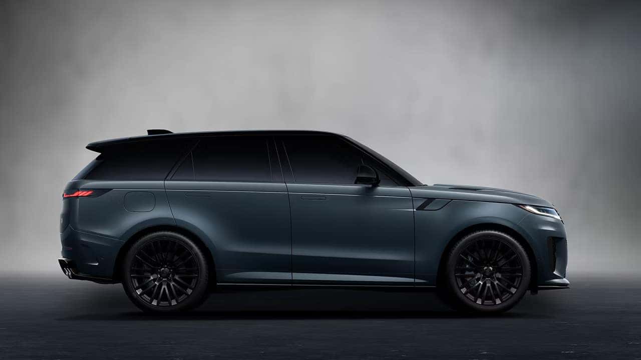Side profile of dark blue Range Rover Sport with black wheels and trim against gray background
