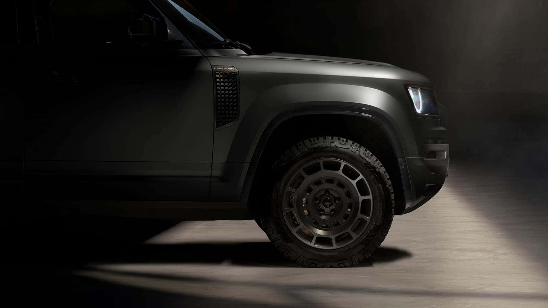Close-up of Land Rover Defender wheel and front quarter panel in studio lighting