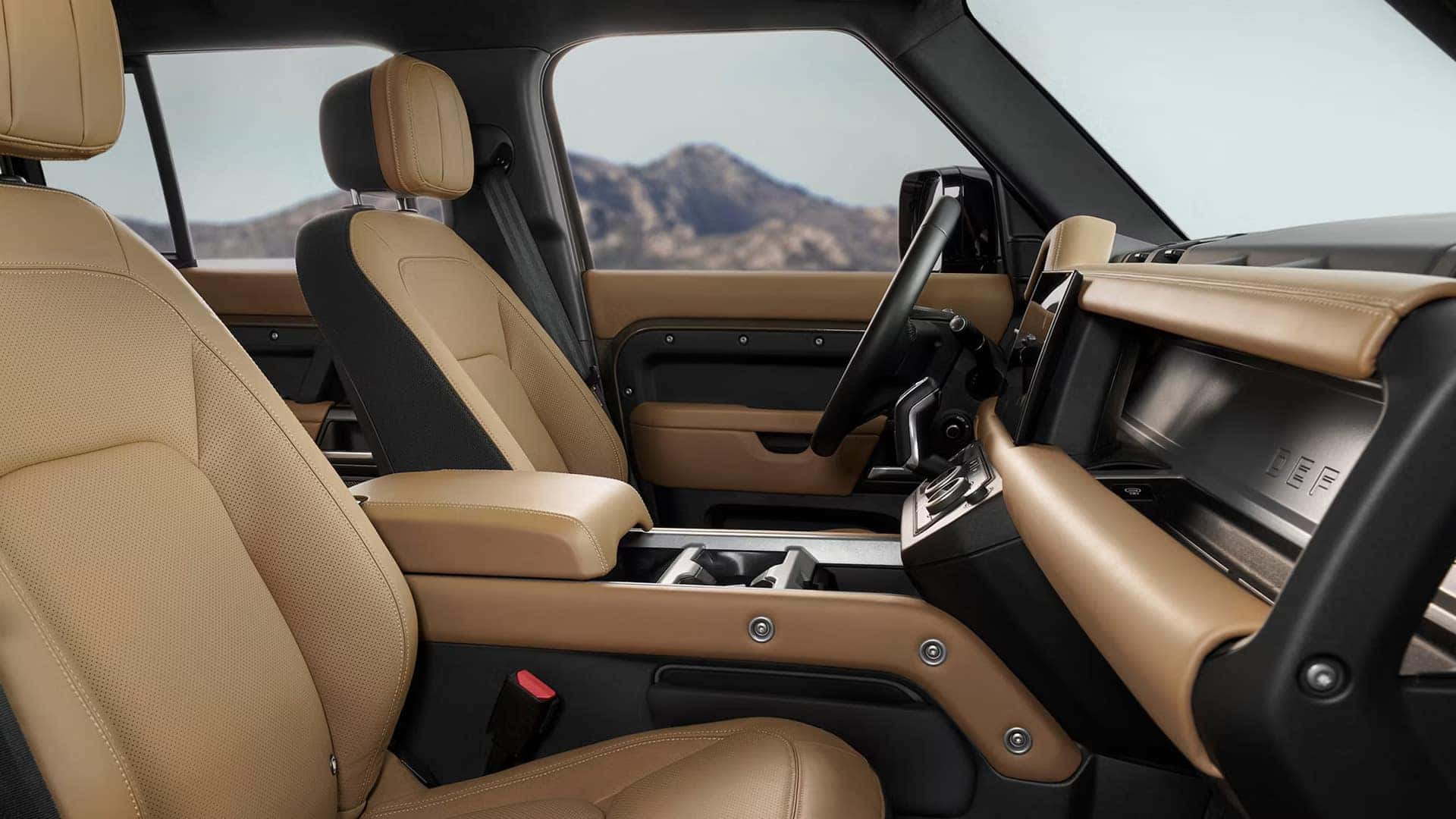 Luxury SUV interior with tan leather seats and dashboard, showing a view of mountains through the windshield