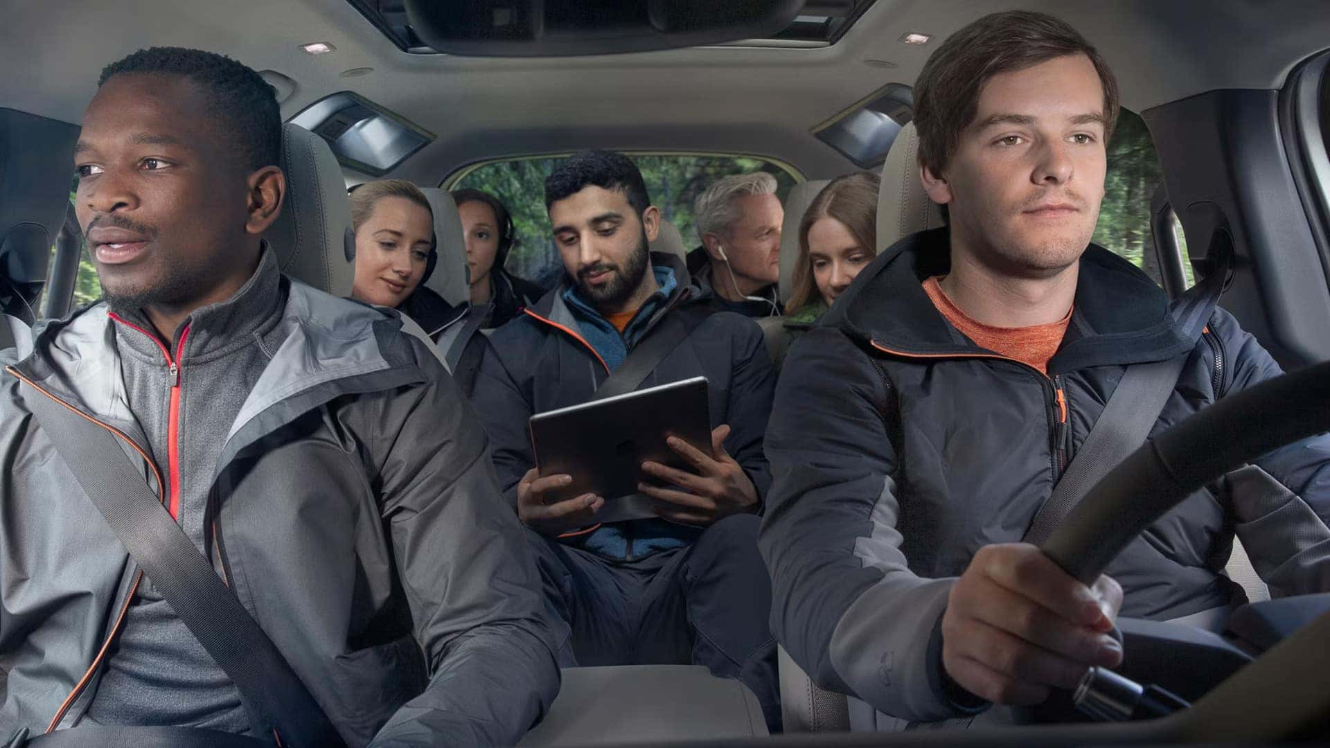 Interior of SUV showing seven passengers with driver and multiple rows of seating with panoramic sunroof