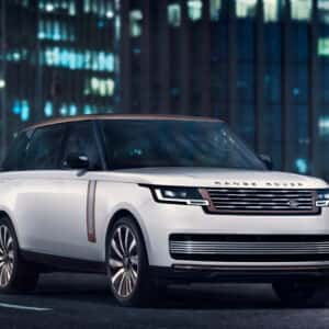 a white range rover driving in the city at night.