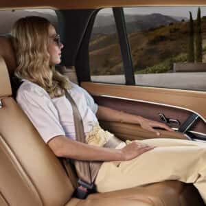 a woman sitting in the backseat of a range rover next to a house.