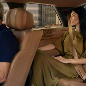 a man in the passenger front seat with a woman in the backseat in a range rover