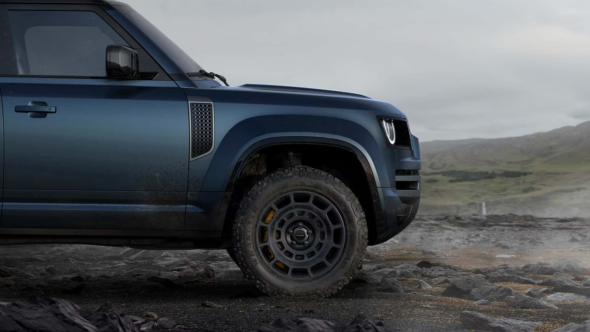 a 2026 land rover defender 110 driving over a rocky and wet terrain