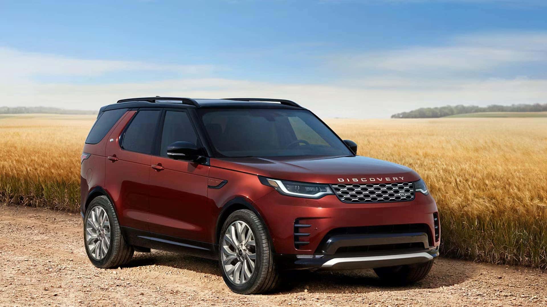 a red 2026 Land Rover Discovery parked next to a field