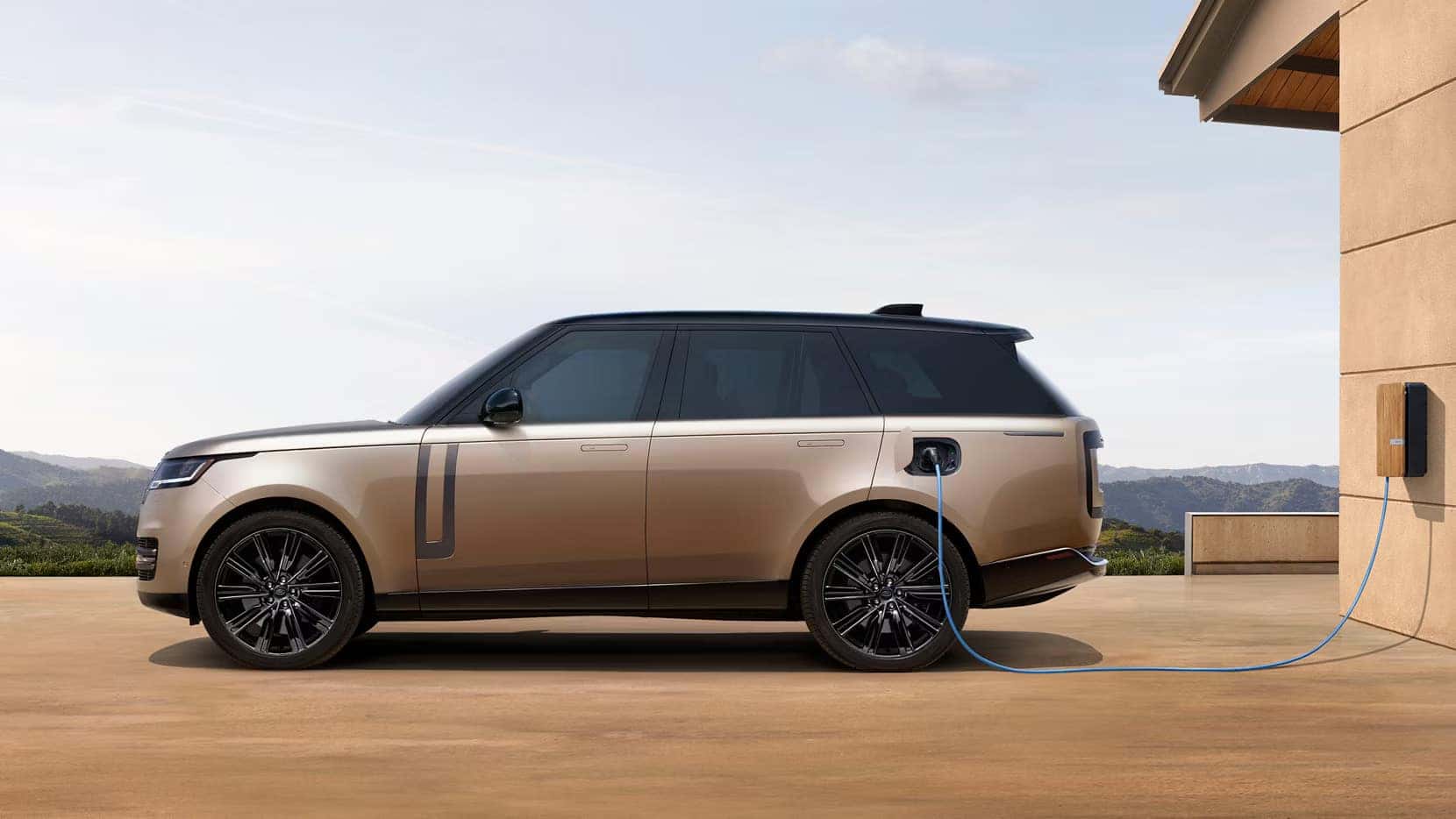 2026 Range Rover parked outside of a home plugged into a charger station