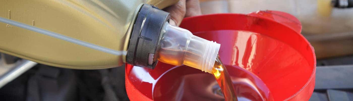 Car servicing mechanic pouring fresh oil to engine