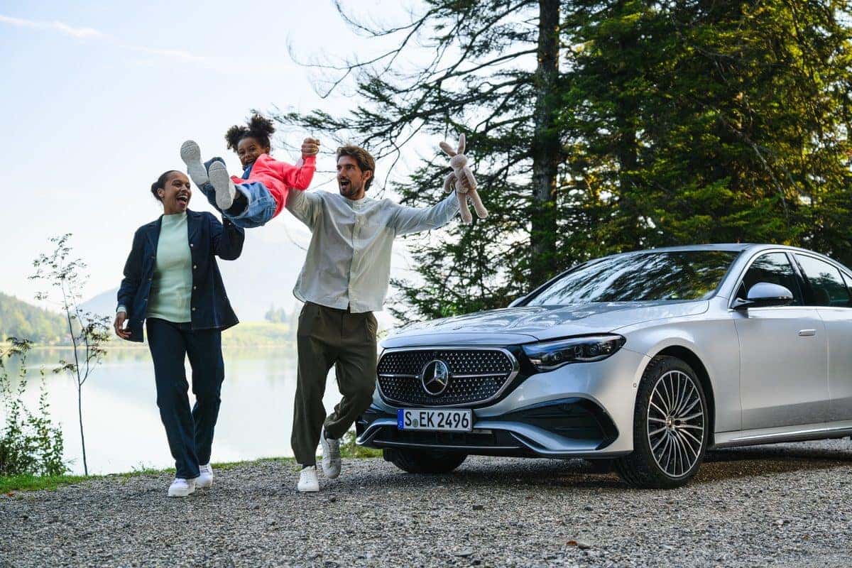 Family walking beside a silver Mercedes-Benz E-Class