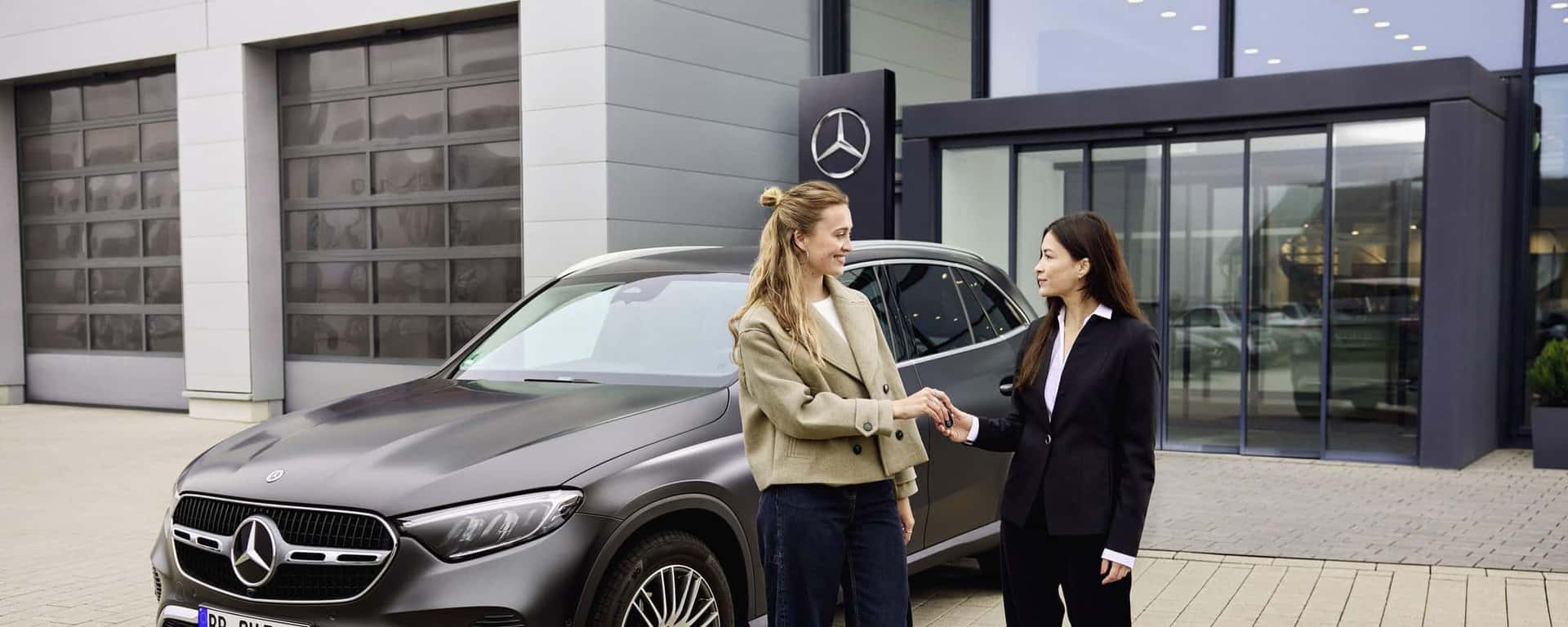 Mercedes-Benz service advisor welcomes a client beside a GLC