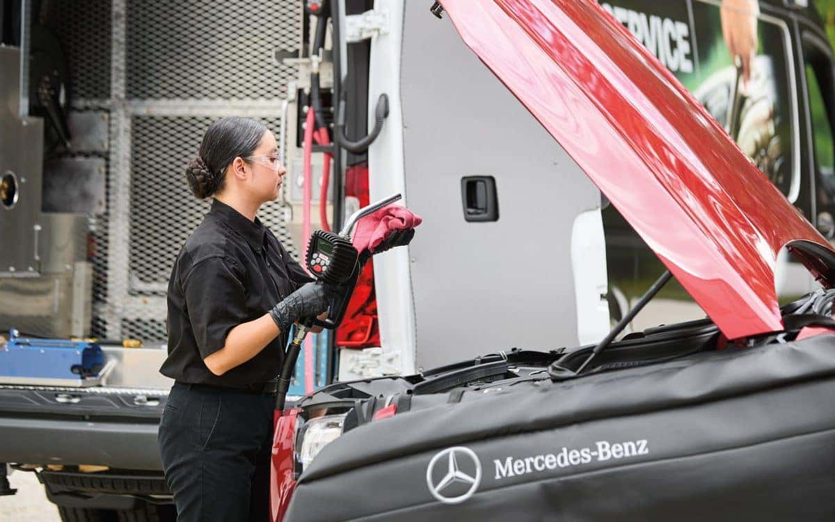 Mercedes-Benz technician helping with a jump start beside a Mercedes-Benz mobile service van