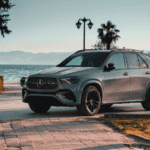 Gray Mercedes-Benz SUV parked along a scenic waterfront with mountains in the background.