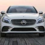 Front of white C-Class sedan facing camera in front of a pink sky at dusk