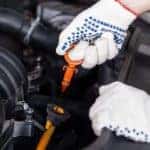 Close up of gloved hands performing an oil change