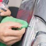 Close up of hands detailing the side of a car