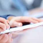 Close of up man's hand signing financial papers